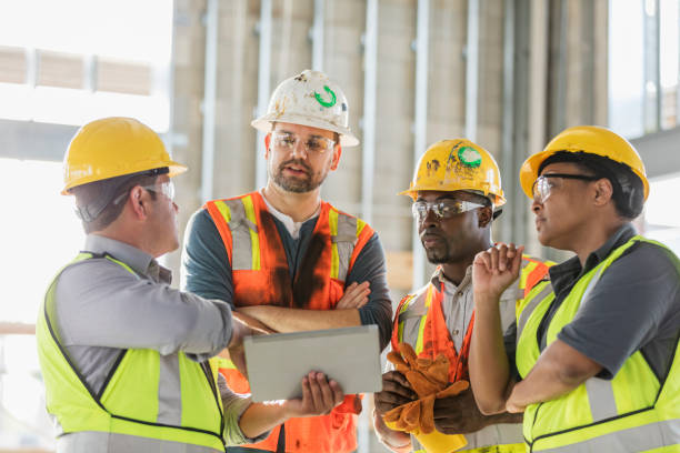 bauarbeiter schauen auf digitales tablet - construction worker construction building contractor hardhat stock-fotos und bilder