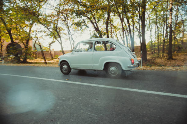 A vintage cars steering wheel and classic dashboard can be seen through the car window in a closeup view