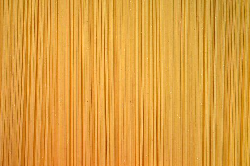Thin spaghetti closeup top view. Uncooked spaghetti background, flour products.