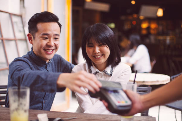 istock Asian young couple paying by smart phone in restaurant 1202391394