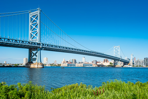 Ben Franklin Bridge and the Delaware River in downtown Philadelphia USA on a sunny blue sky day.