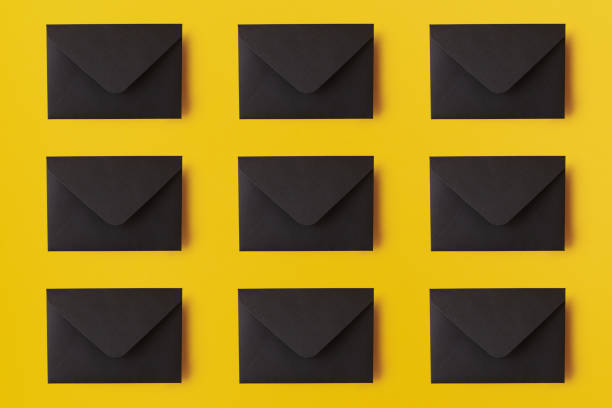 istock Black envelopes on the yellow background. Mail concept 1202393000
