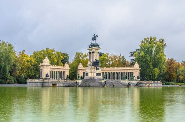 istock monument to King Alfonso XII, featuring a semicircular colonnade and an equestrian statue of the monarch on the top of a tall central core near the lake in Buen Retiro Park. Madrid, Spain 1202393214