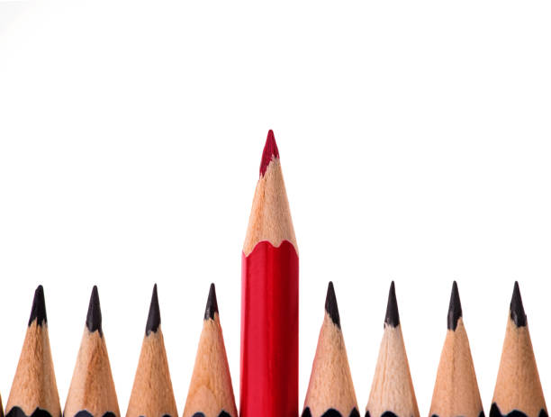 istock Red pencil standing out from crowd of plenty identical black fellows on white background. business success concept 1202397311