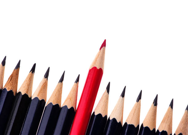 istock Red pencil standing out from crowd of plenty identical black fellows on white background. business success concept 1202397315