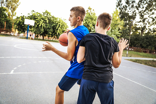 Teenagers playing basketball outdoors