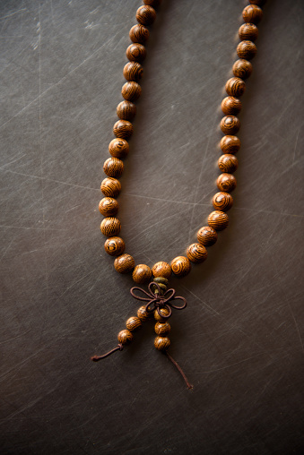 Hand holding black tasbih or Rosario on the wooden background.