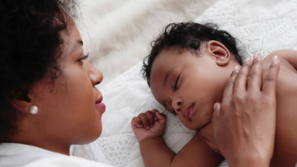 istock african american baby boy sleeping on bed while mother watching with love 1202406183