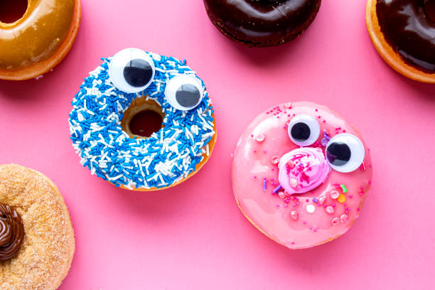 istock A blue donut with a pink donut with funny faces on a pink background looking each other 1202411199