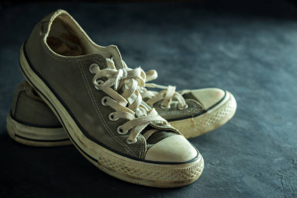 istock Dirty sneaker in darkness. Closeup old sneaker on black cement floor. 1202412782