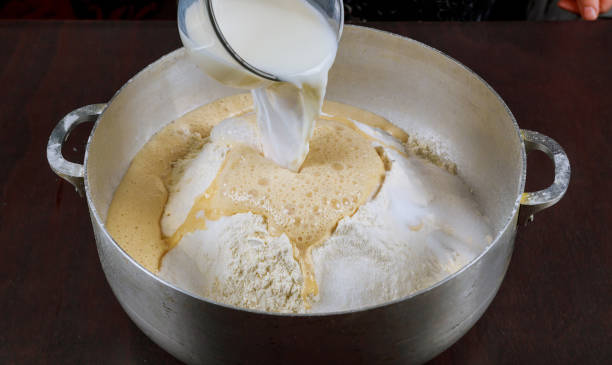 istock Pouring milk on yeast dough for making bread. 1202422114