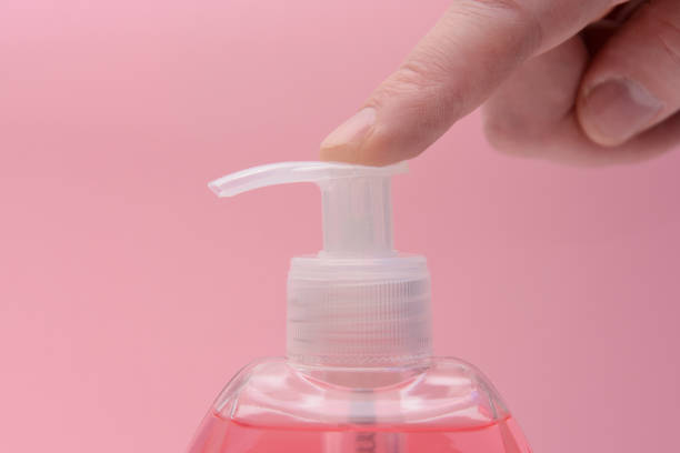 distributeur liquide de savon avec le doigt pushable, sur un fond rose - corps de femme en transparence photos et images de collection