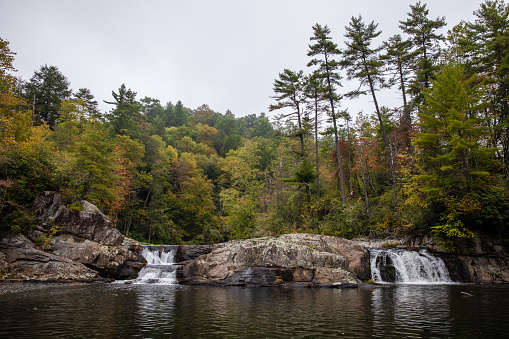 North Carolina Blue Ridge Mountains Linville Falls in Autumn. Beautiful fall colored trees surrounding the waterfalls. Lake below.