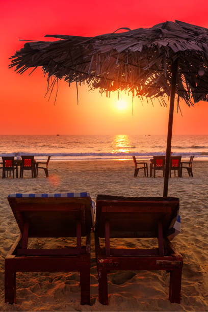 sonnenuntergang am tropischen strand mit liegestühlen unter ubrellas - goa stock-fotos und bilder