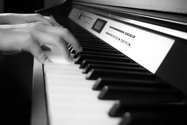 istock Young hands are playing the piano. Side view 1202431429