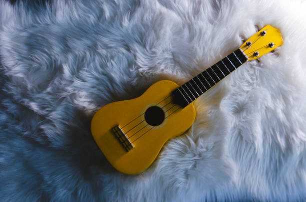 istock Yellow Ukulele Resting on a White Soft Fluffy Blanket 1202431508