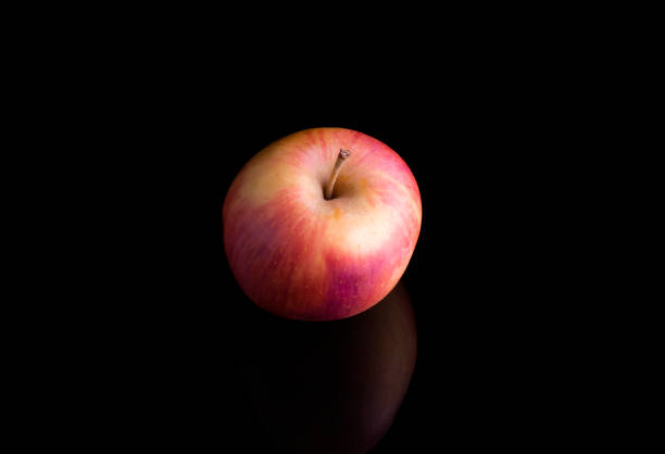 pink juicy Apple on a black background with reflection.