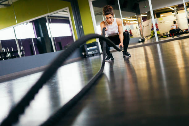 istock Young and athletic woman using training ropes in a gym. 1202434411