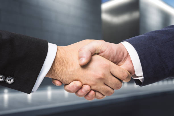 istock Two businessmen shake hands in the evening on a abstract exterior backgrond. Insider concept 1202440814