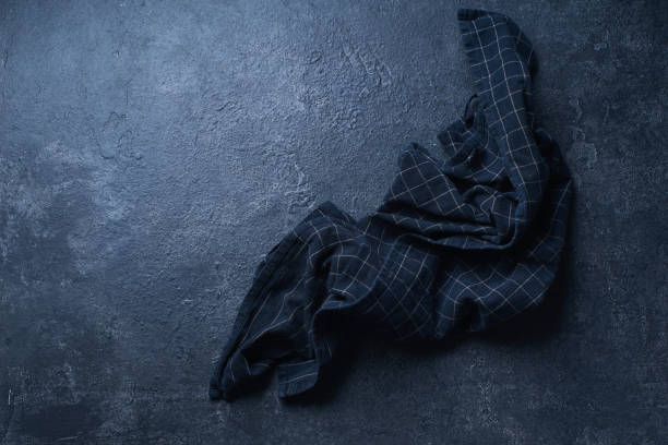 istock Top view image with dark textured kitchen table and black checkered cotton towel. Flatlay with copy space 1202442249