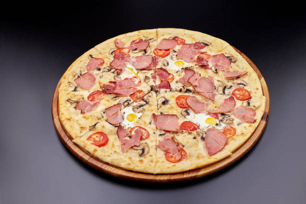 istock Carbonara pizza with bacon and egg on beautiful grey table. Isolated on dark background. 1202442666
