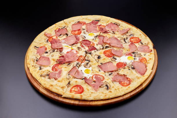 istock Carbonara pizza with bacon and egg on beautiful grey table. Isolated on dark background. 1202442682