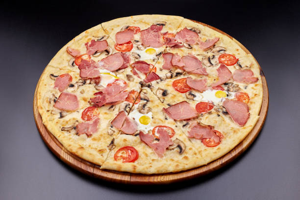 istock Carbonara pizza with bacon and egg on beautiful grey table. Isolated on dark background. 1202442706