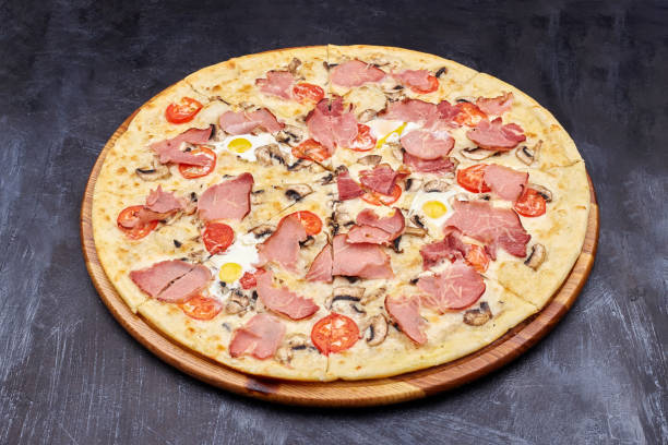 istock Carbonara pizza with bacon and egg on beautiful grey table. Isolated on dark background. 1202442724
