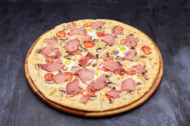 istock Carbonara pizza with bacon and egg on beautiful grey table. Isolated on dark background. 1202442732