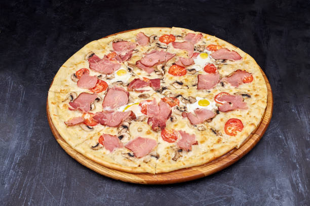 istock Carbonara pizza with bacon and egg on beautiful grey table. Isolated on dark background. 1202442744