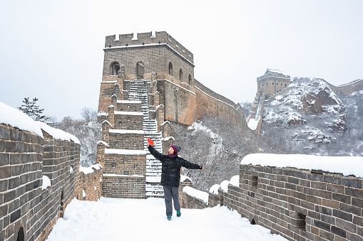 A Chinese woman holding a small five-star red flag on the Great Wall of China