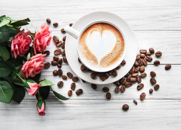 una taza de café con patrón cardíaco en una mesa - coffee bean coffee flower ribbon fotografías e imágenes de stock
