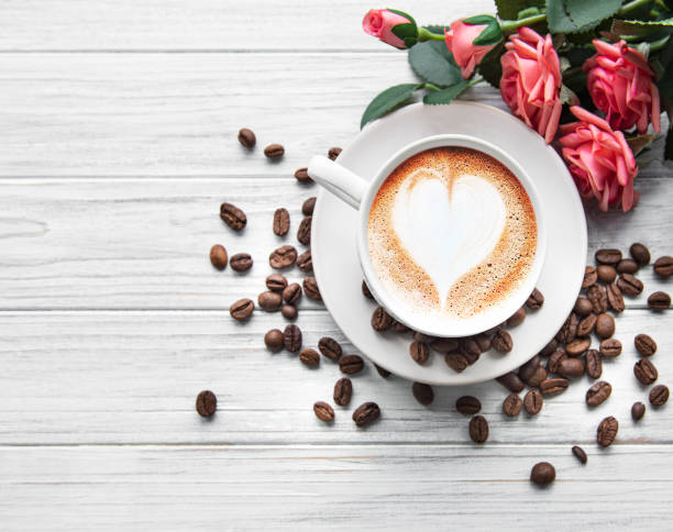 eine tasse kaffee mit herzmuster auf einem tisch - coffee bean coffee flower ribbon stock-fotos und bilder