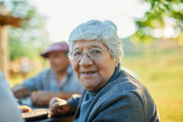 senior woman looking at camera and smiling while sitting at the table. - spring happiness women latin american and hispanic ethnicity imagens e fotografias de stock