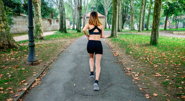 istock Female athlete running through a park 1202446362