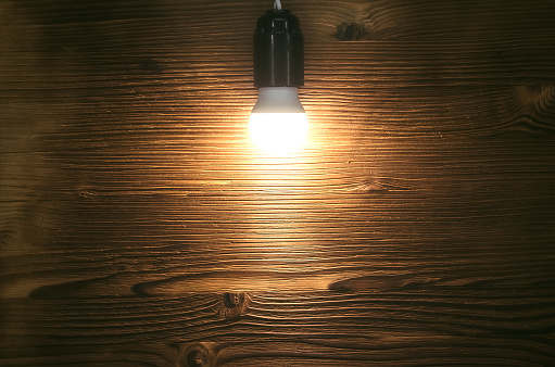 Burning bulb lamp on wooden surface background with copy space. New idea. Billboard. Message board.