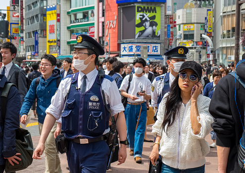 People wearing face masks on a busy street in Ginza, Tokyo.