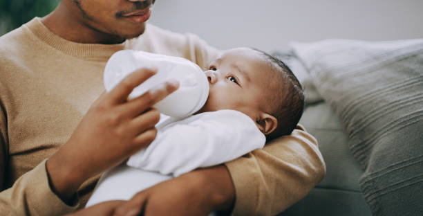My boy deserves the best start in life Shot of an adorable baby boy being bottle fed milk at home by his father father and baby stock pictures, royalty-free photos & images