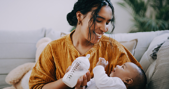 Shot of a young woman feeding her adorable baby boy bottled milk at home