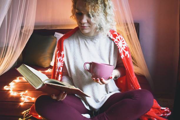 istock Woman in bed at winter, reading a book 1202455928