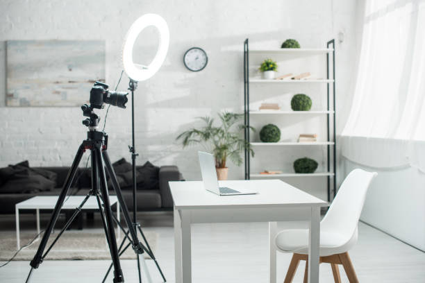 istock digital camera on tripod near ring lamp and table with laptop 1202456551