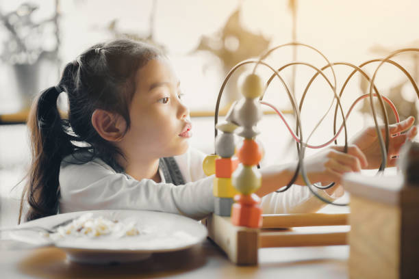 istock An Asian girl is playing toys while eating. 1202458856