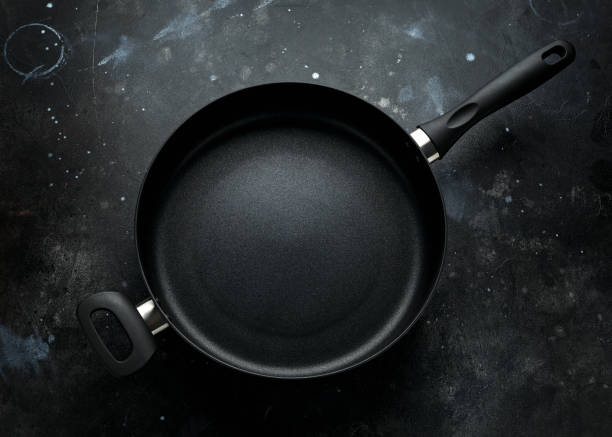 istock new non-stick aluminium frying pan on dark background 1202459950