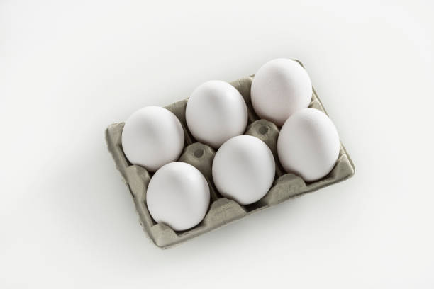 istock Six White eggs on cardboard box gray carton on white 1202460363