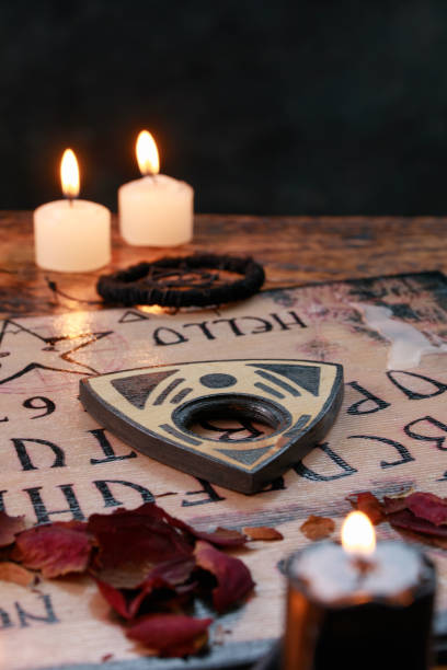 Spiritual board ouija with candles close-up. Mystical ritual of calling dead spirits. Macro. stock photo
