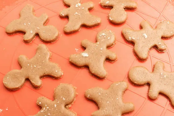 Gingerbread men cookies background. Dough gingerbread men on silicon baking mat.
