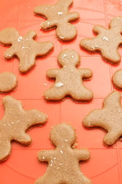 Christmas gingerbread men cookies background. Dough gingerbread men on silicon baking mat.