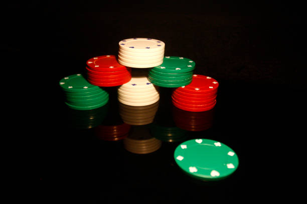 istock Stack of poker chips with a green chip in front and reflections isolated on black 1202465146