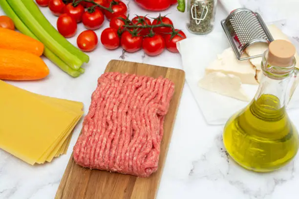 Photo of Minced meat with lasagna sheets, parmesan cheese, bottle of olive oil and vegetables for preparing Italian pasta