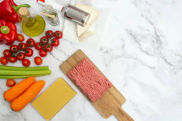 Photo of Top view and flat lay of ingredient for cooking an Italian classical lasagna with Bolognese sauce on marble background with copy space for your text